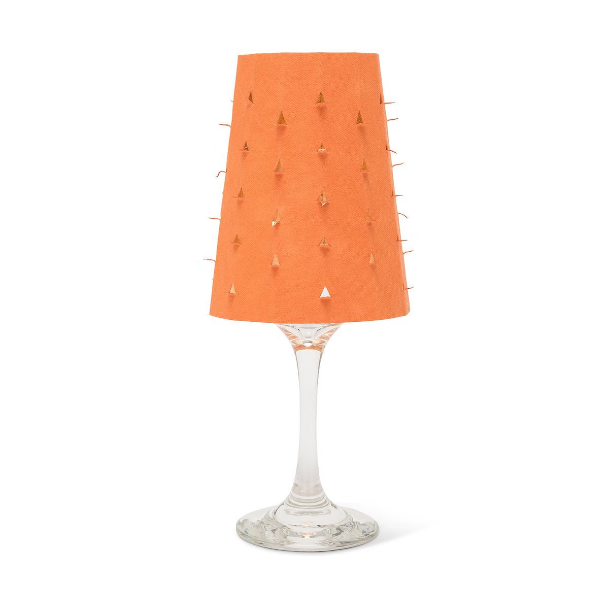 An orange washable paper lampshade with cut out details is shown sitting atop a wine glass.