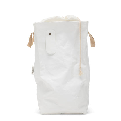 A washable paper laundry bag is shown in white. It features two side handles, a popper tab, and an interior drawstring lining.