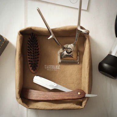 A tan washable paper tray is shown containing a shoe brush and a knife.