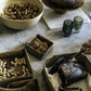 A series of washable paper trays adorn a marble table top. They contain walnuts, peanuts, biscuits, and a cake. They are all of varying sizes.
