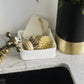 A grey washable paper tray sits atop a marble sink, containing dish brushes.