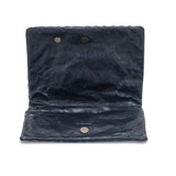 A washable paper folded clutch is shown open in navy, with a metallic stud closure and UASHMAMA logo stamp in silver.