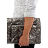 A person is shown holding two metallic pewter washable paper clutches - one large and one small.