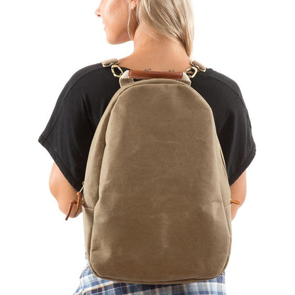 A blonde woman is shown wearing a washable paper backpack. It has two side zip toggles, is oval in shape and it is sand in colour.