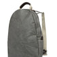 An oval washable paper backpack is shown from a 3/4 angle. It has a top handle, two adjustable canvas shoulder straps, and is grey in colour.