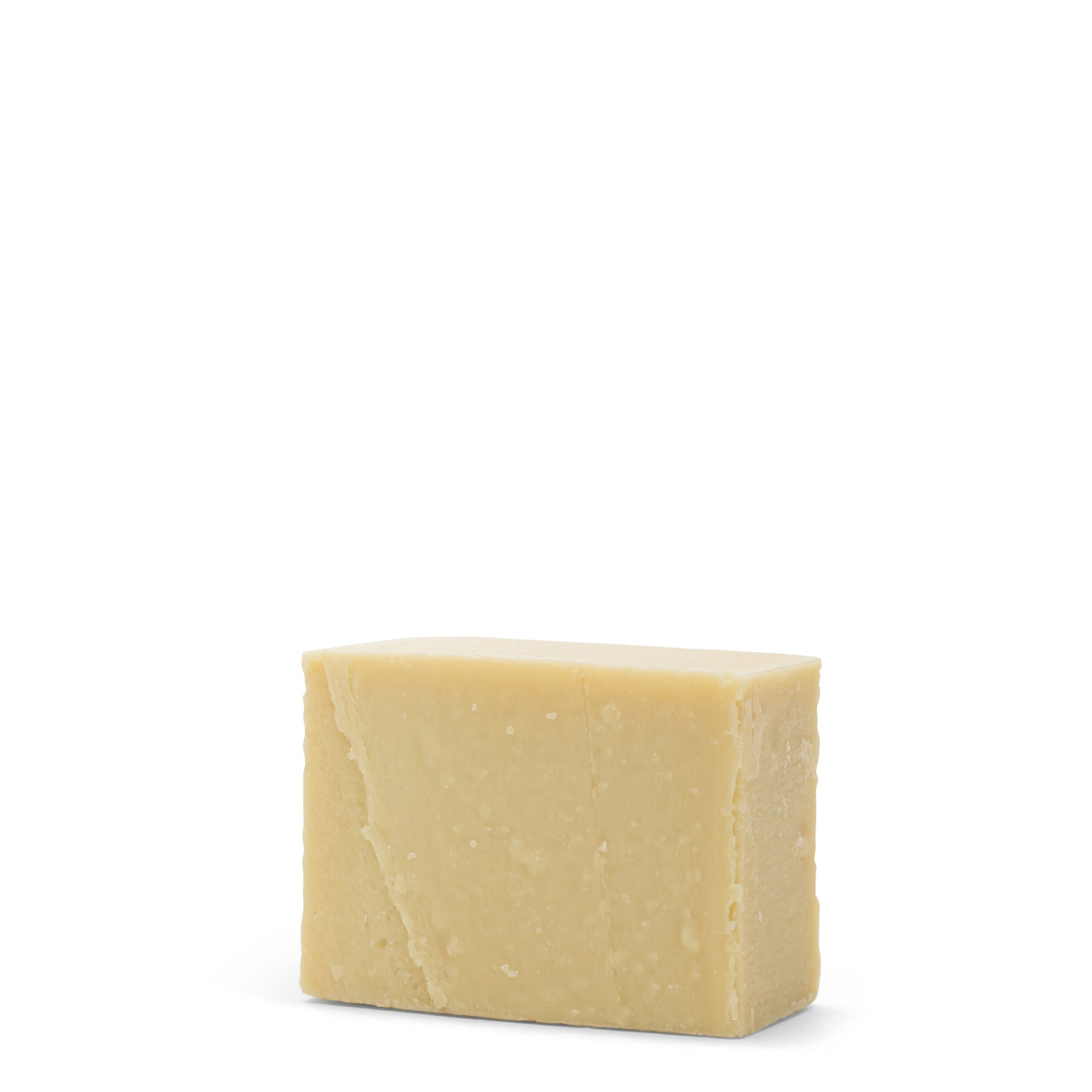 A rectangular soap sits unwrapped on a white background. It is creamy yellow in colour.