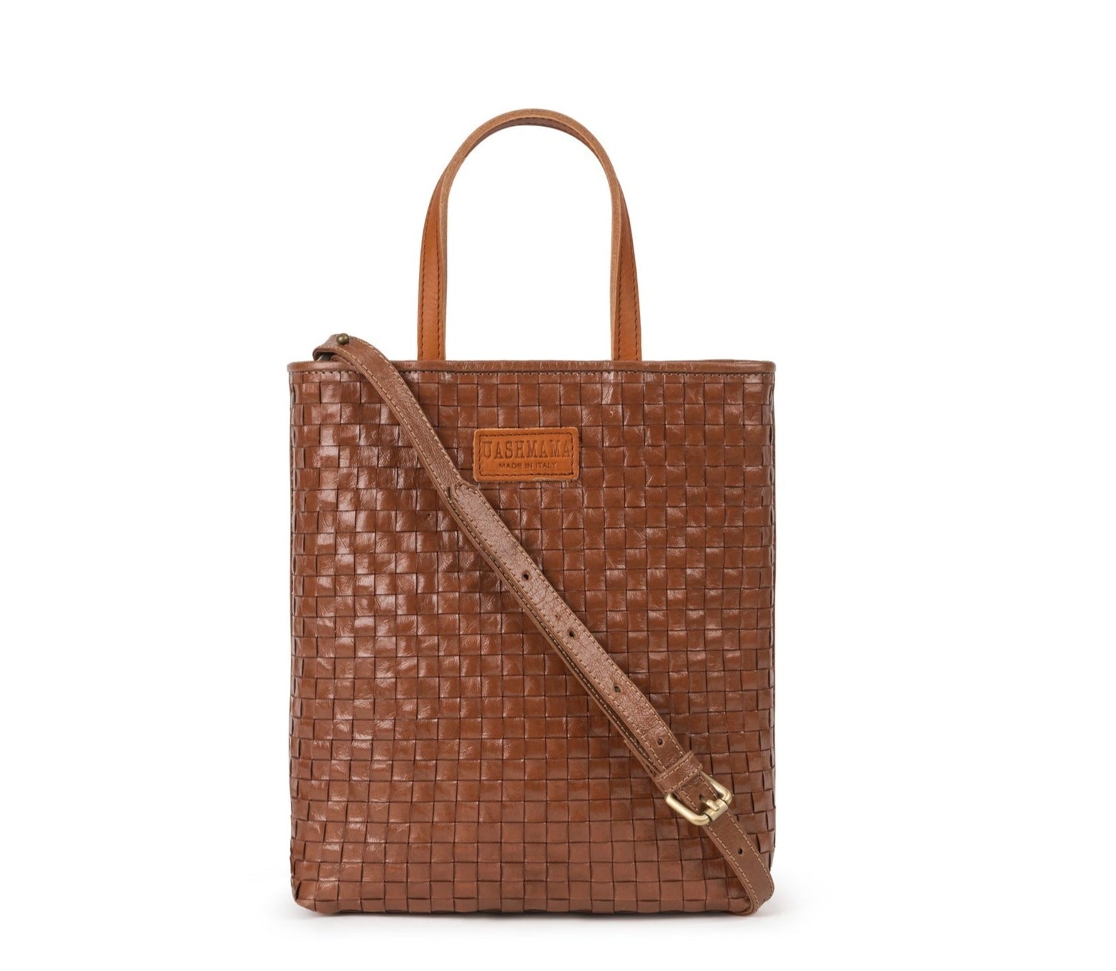 A woven washable paper tote bag is shown from the front angle. It has two top handles and a long shoulder strap. It is brown in colour.