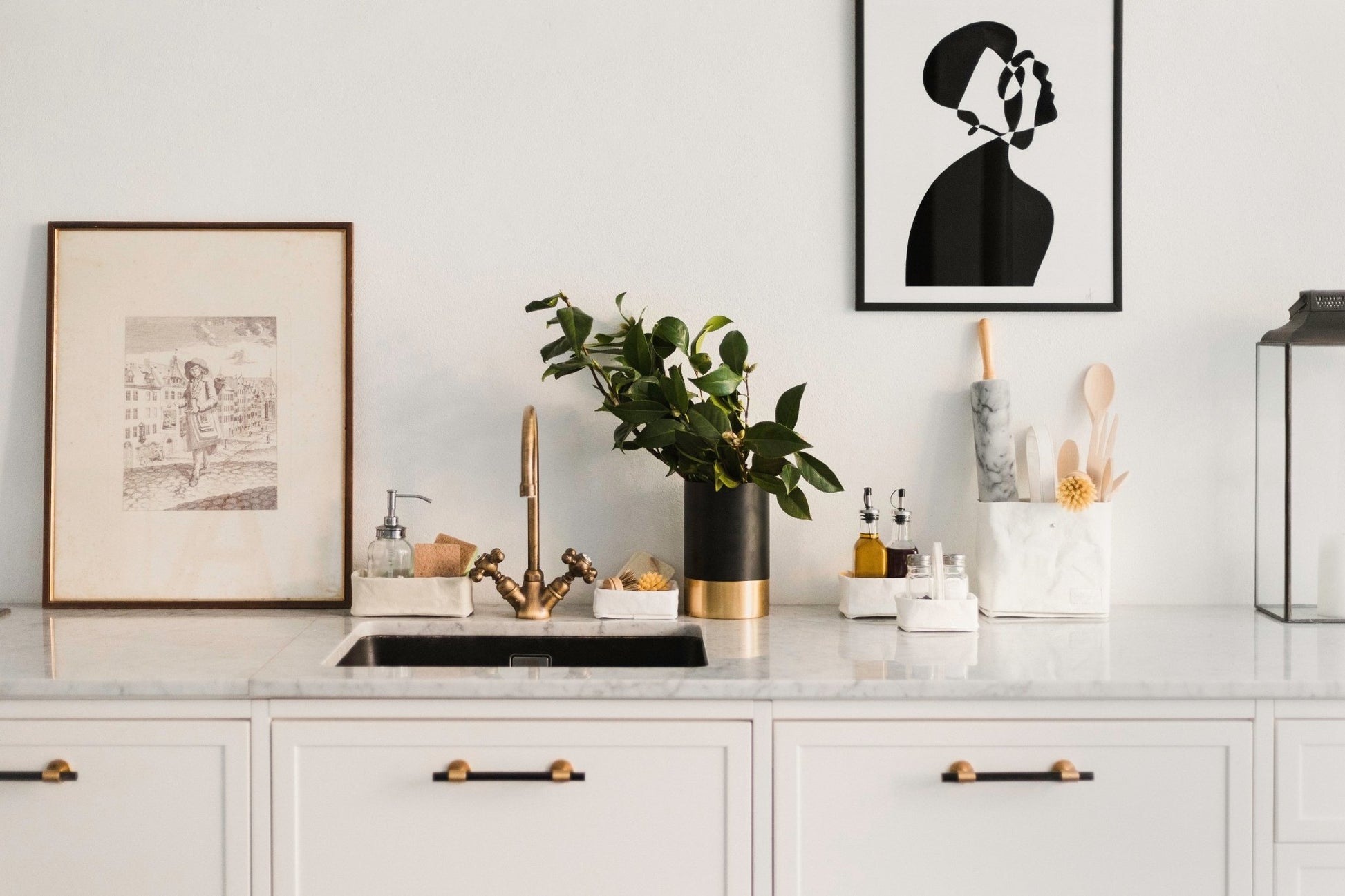 A marble kitchen counter top displays art work, three white washable paper trays and two white washable paper utensil holders.