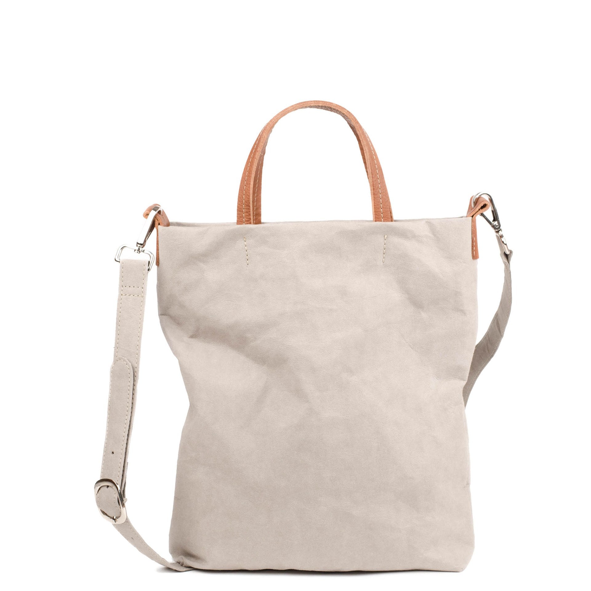 A washable paper tote bag is shown from the front angle. It has a relaxed shape, two top handles and a long shoulder strap. It is pale grey in colour.