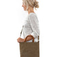 A blonde woman is shown from the side wearing casual clothing. She wears a crossbody washable paper tote bag with top handles. It is khaki in colour.