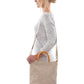 A blonde woman is shown from the side wearing casual clothing. She wears a crossbody washable paper tote bag with top handles. It is beige in colour.