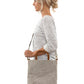 A blonde woman is shown from the side wearing casual clothing. She wears a crossbody washable paper tote bag with top handles. It is pale grey in colour.