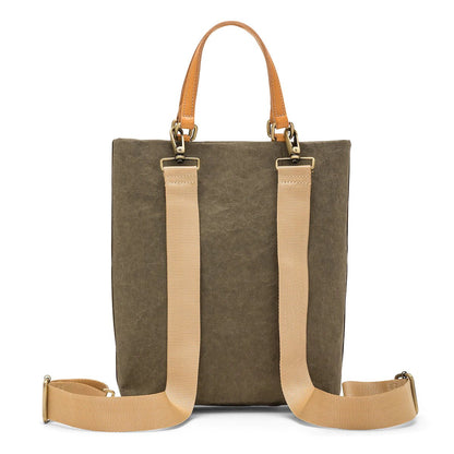 A rectangular tote bag backpack is shown from the back angle. It features two top tote handles, and two adjustable canvas shoulder straps. It is grey-brown in colour.