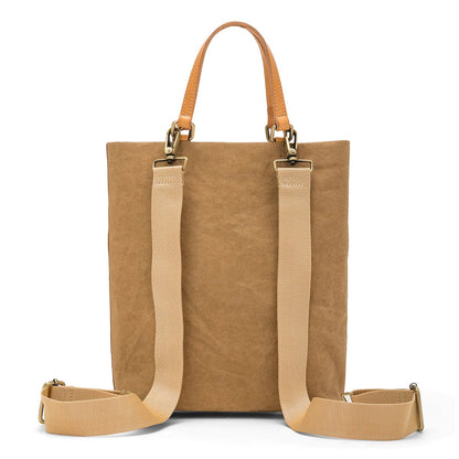 A rectangular tote bag backpack is shown from the back angle. It features two top tote handles, and two adjustable canvas shoulder straps. It is natural tan in colour.