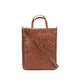 A woven washable paper tote bag is shown from the front angle. It features two top handles and a long adjustable shoulder strap. It is brown in colour.