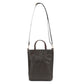 A washable paper tote bag is shown with a long shoulder strap and two top handles. The fabric is woven and it is chocolate brown in colour.