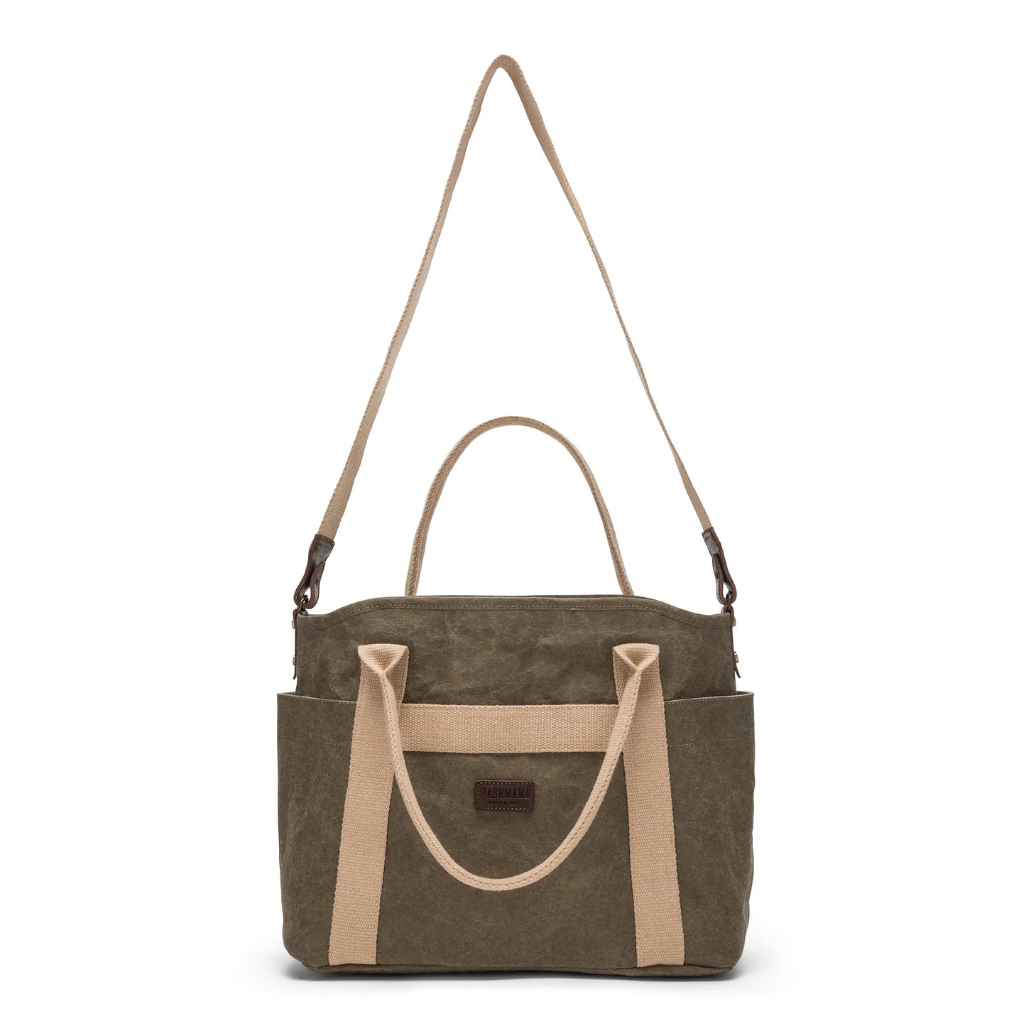A large washable paper shopper bag is shown from a front angle. It features a long canvas shoulder strap and two top handles. It has an external pocket running the length of the bag, and the UASHMAMA logo stamped in the front. It is shown in a khaki colour.