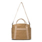 A washable paper shopper bag is shown from the back angle. It features a canvas long shoulder strap, two canvas handles, and an exterior pocket running the length of the bag. It has a zip top closure and is shown in a sandy tan colour.