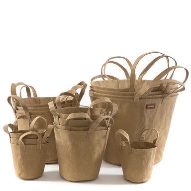 A selection of washable paper baskets are shown stacked in one another, in four varying sizes. They are shown in a sand colour. 