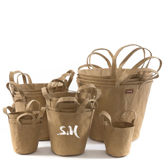 A selection of washable paper baskets are shown stacked in one another, in four varying sizes. They are shown in a sand colour, and the basket in the middle is labelled "SM."