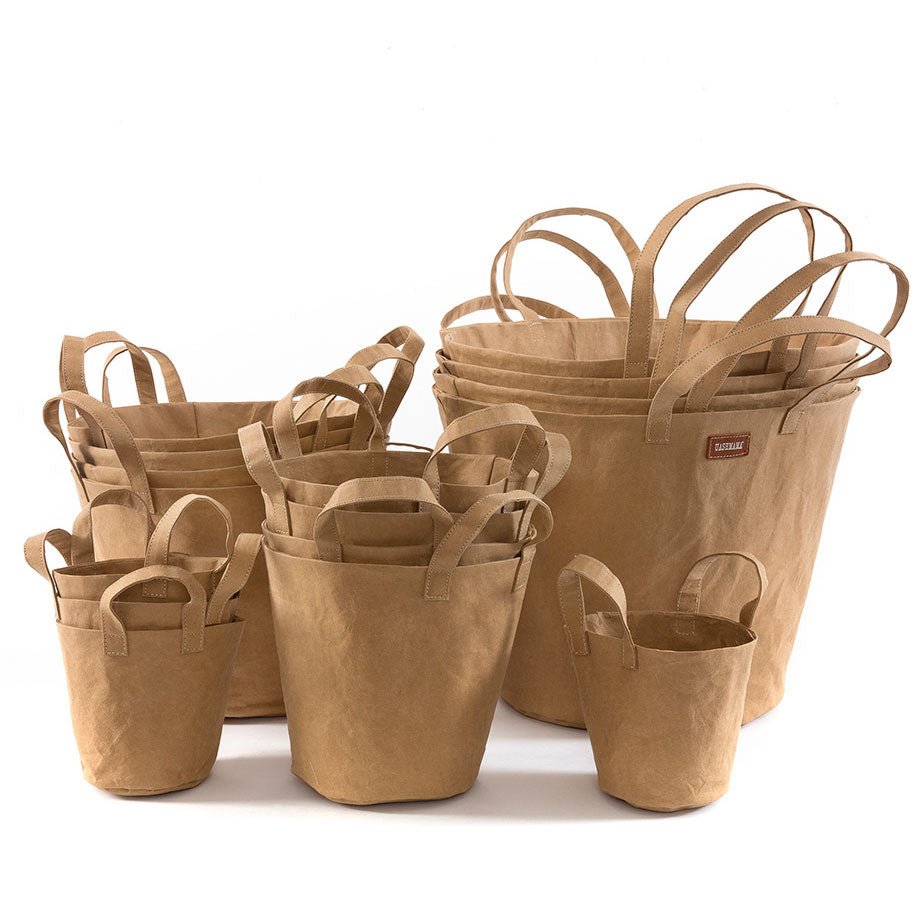 A selection of washable paper baskets are shown stacked in one another, in four varying sizes. They are shown in a sand colour.
