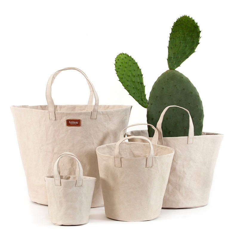 Four individual washable paper baskets are shown in varying sizes. The one at right contains a large cactus, and they are shown in a cream colour.