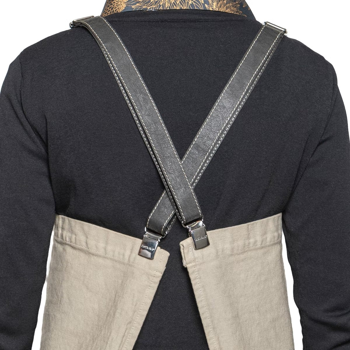 A person is shown from the back wearing a black long-sleeved t-shirt and a washable paper apron with washable paper and metal clip straps. The apron is beige in colour.