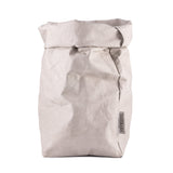 A washable paper bag is shown. The bag is rolled down at the top and features a UASHMAMA logo label on the bottom left corner. The bag pictured is the extra large size in light grey.