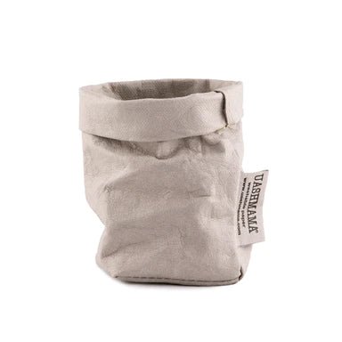 A washable paper bag is shown. The bag is rolled down at the top and features a UASHMAMA logo label on the bottom left corner. The bag pictured is the extra small size in pale grey.