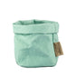A washable paper bag is shown. The bag is rolled down at the top and features a UASHMAMA logo label on the bottom left corner. The bag pictured is the piccolo size in pale turquoise.
