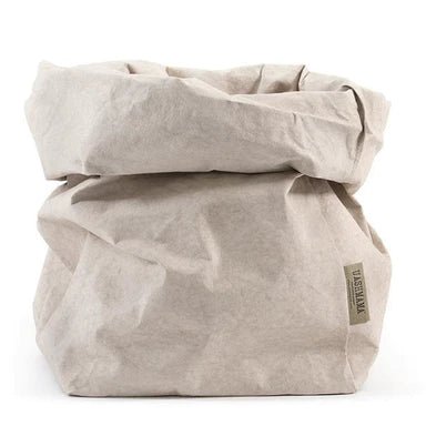 A washable paper bag is shown. The bag is rolled down at the top and features a UASHMAMA logo label on the bottom left corner. The bag pictured is the extra large size in a cream colour.