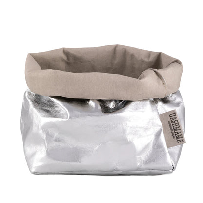 A washable paper bag is shown. The bag is rolled down at the top and features a UASHMAMA logo label on the bottom left corner. The bag pictured is the medium size in metallic silver.