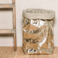 A washable paper bag is shown. The bag is rolled down at the top and features a UASHMAMA logo label on the bottom left corner. The bag pictured is the extra extra large size in metallic platinum. Next to the paper bag is a wooden ladder.