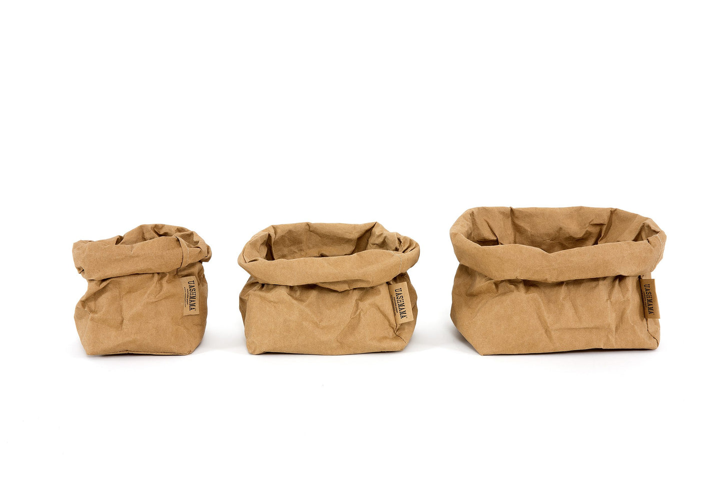 A small, medium and large washable paper bag in a tan colour are lined up from smallest to largest.