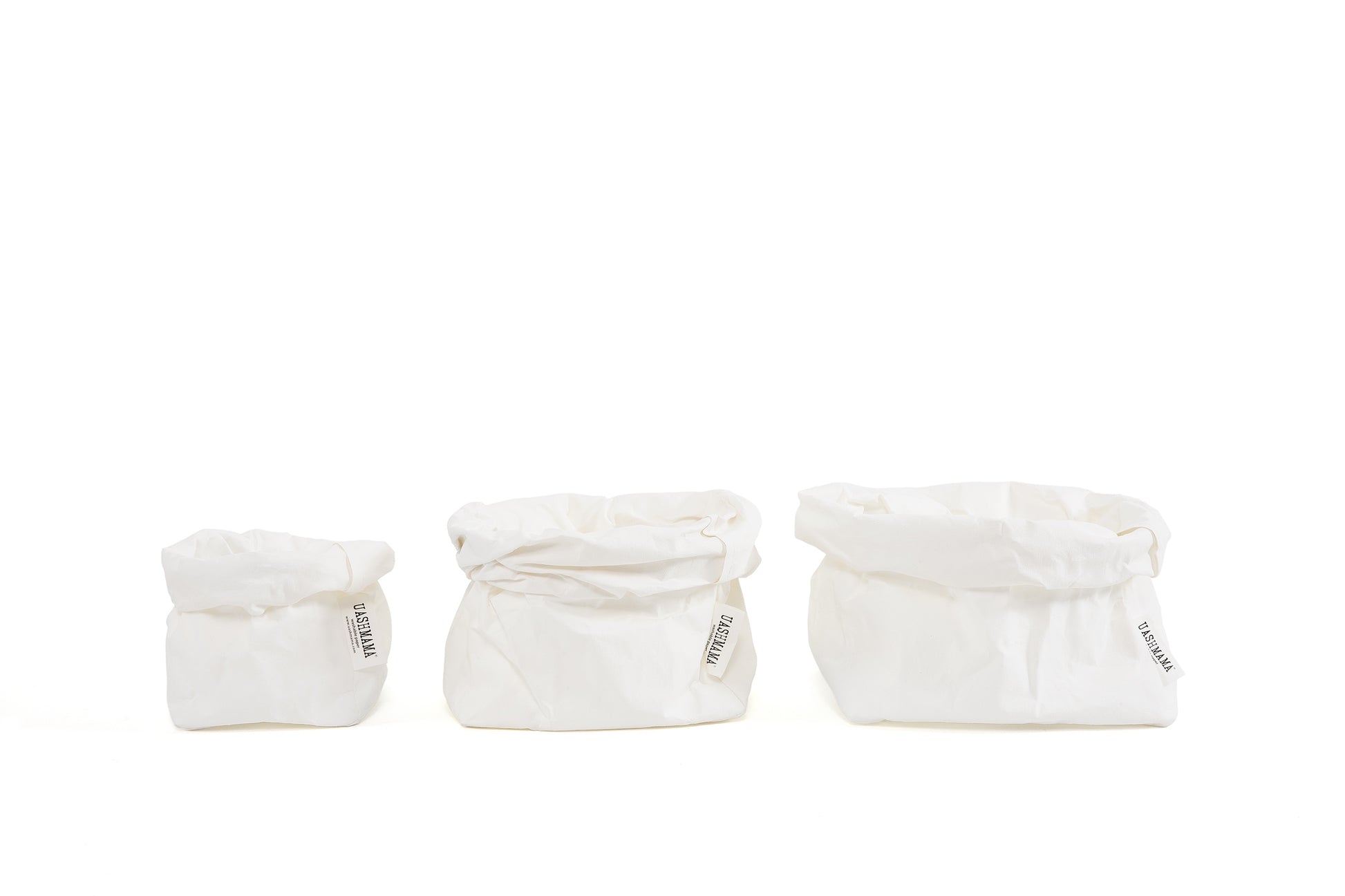 A small, medium and large paper bag in white go from smallest to largest in a horizontal row. 