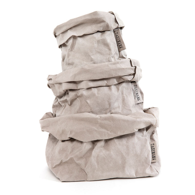 A stack of pale grey washable paper bags, with large on the bottom, medium in the middle and small on top.