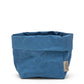 A medium paper bag in denim blue colour. The top is rolled down.