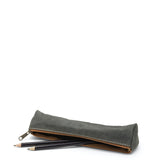 A washable paper pencil case is shown on its side with two pencils spilling out. The pencil case is dark grey in colour and has a metal zip closure.