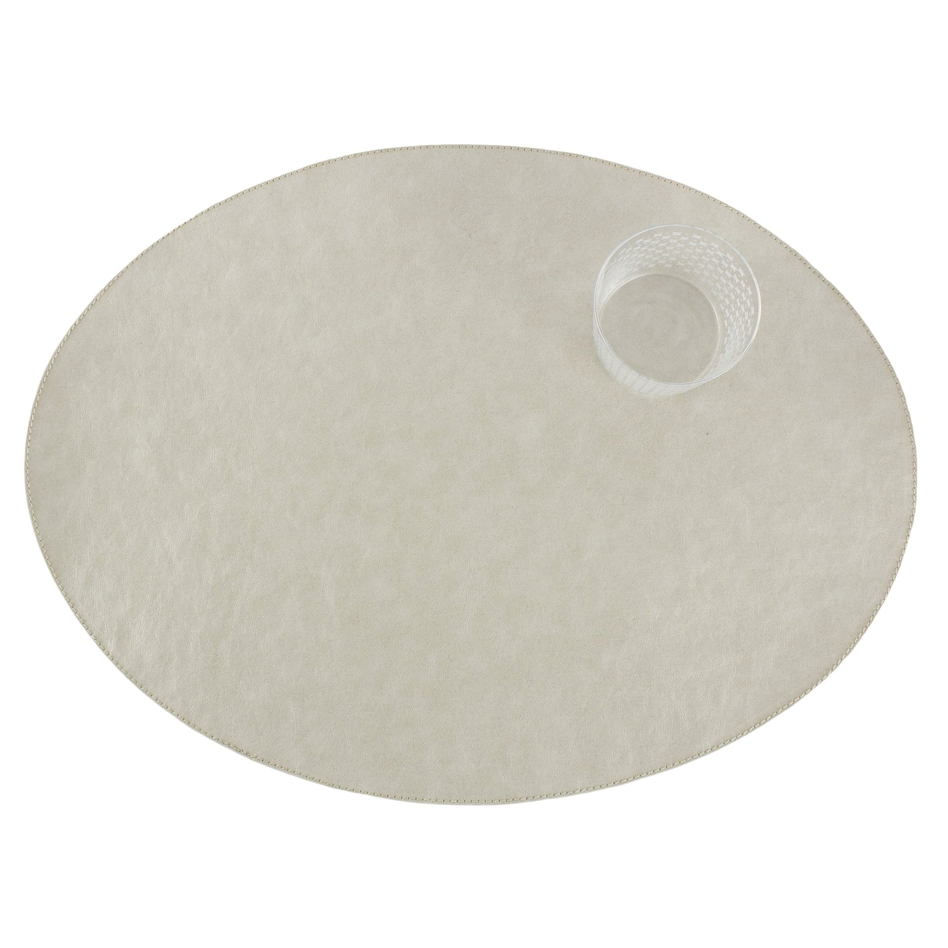 An oval washable paper placemats is shown with a small drinking glass in the upper right hand corner. The placemat shown is cream in colour.