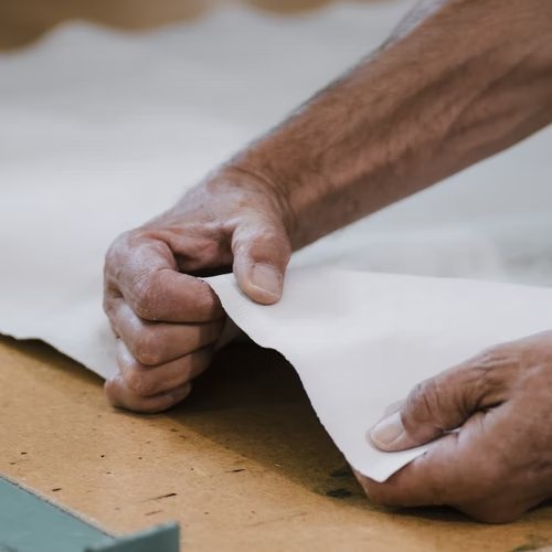 The image shows a man's hands pulling apart a sheet of washable paper material.