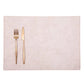 A rectangular washable paper placemat is shown with a rose gold fork and knife set on the left hand side. The placemat is pale pink.