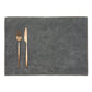 A rectangular washable paper placemat is shown with a rose gold fork and knife set on the left hand side. The placemat is dark grey.