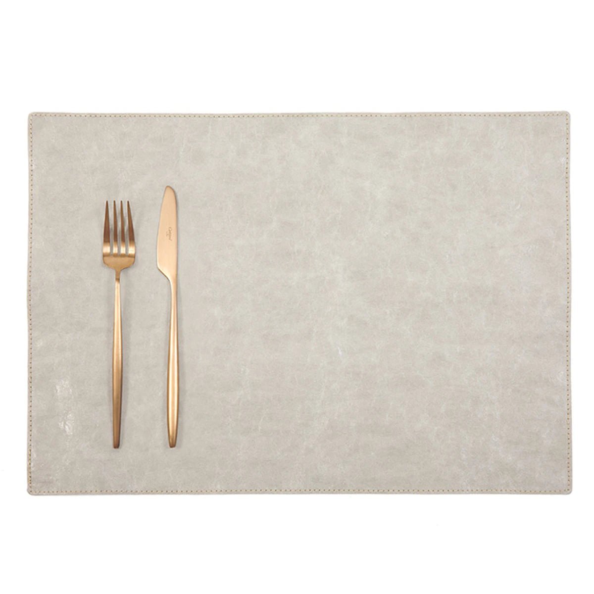 A rectangular washable paper placemat is shown with a rose gold fork and knife set on the left hand side. The placemat is cream.