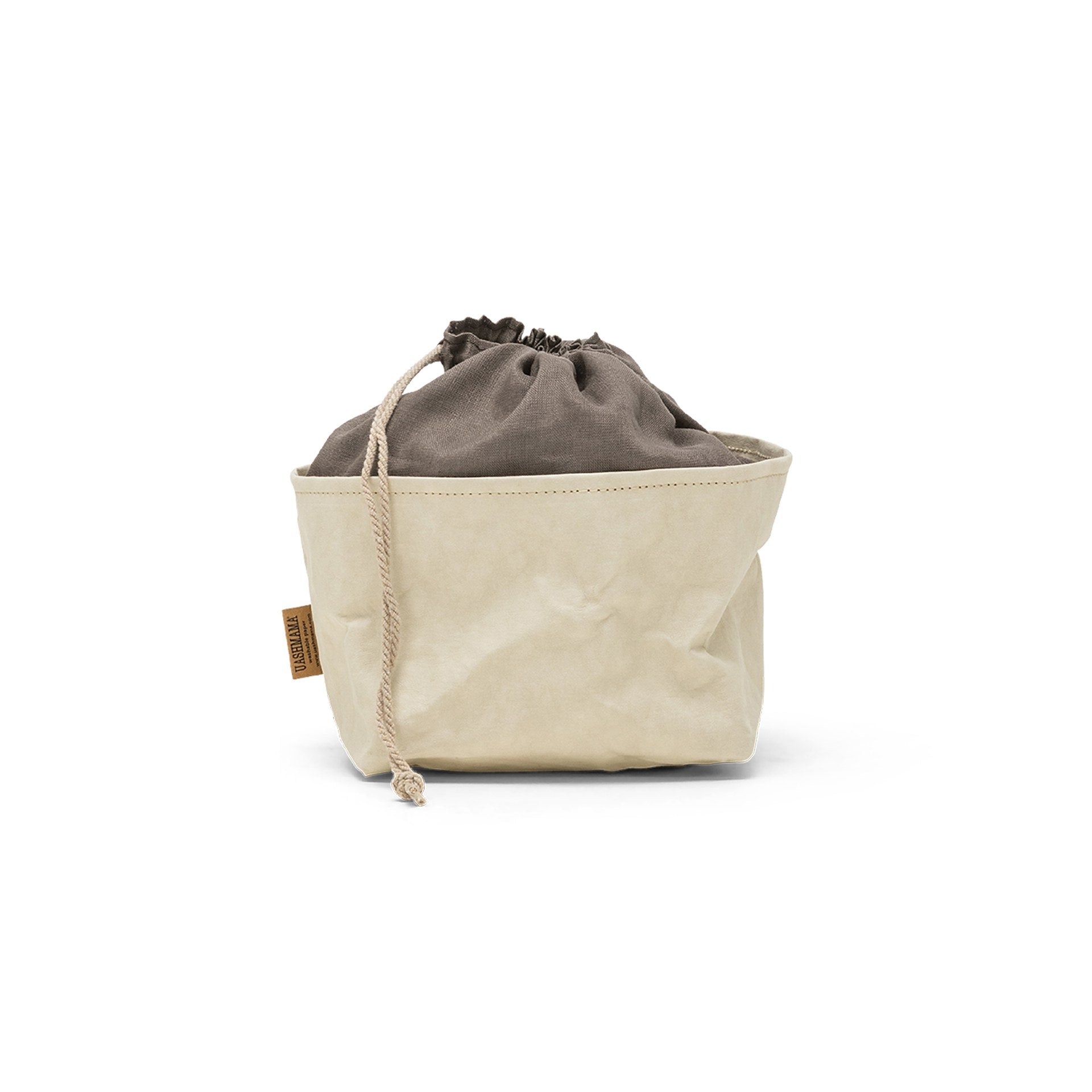 A washable paper bread bag with a drawstring organic linen top is shown. The bag has a small UASHMAMA logo label on the left hand side and fastens with a beige cord drawstring. The bag is cream in colour with a dark grey linen drawstring top.