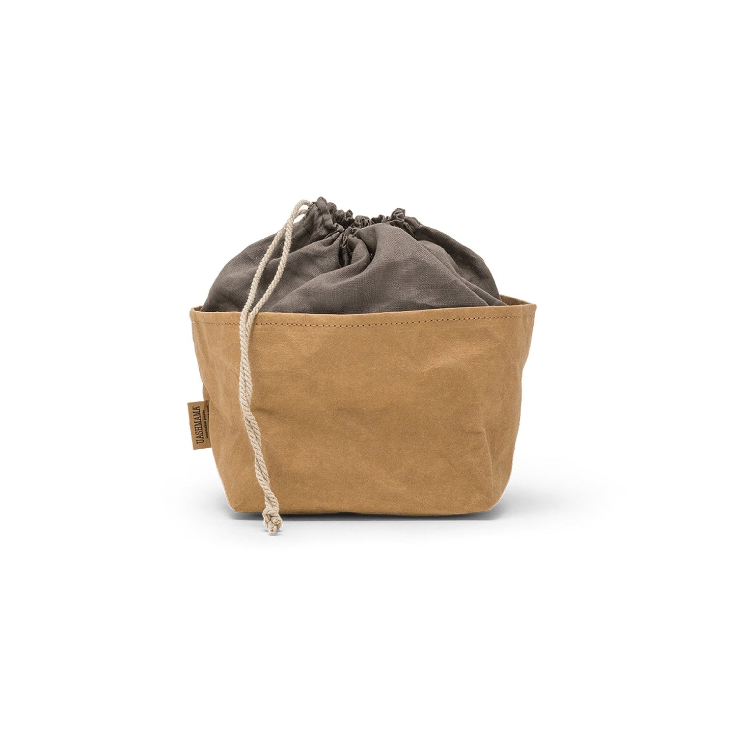 A washable paper bread bag with a drawstring organic linen top is shown. The bag has a small UASHMAMA logo label on the left hand side and fastens with a beige cord drawstring. The bag is tan in colour with a dark grey linen drawstring top.