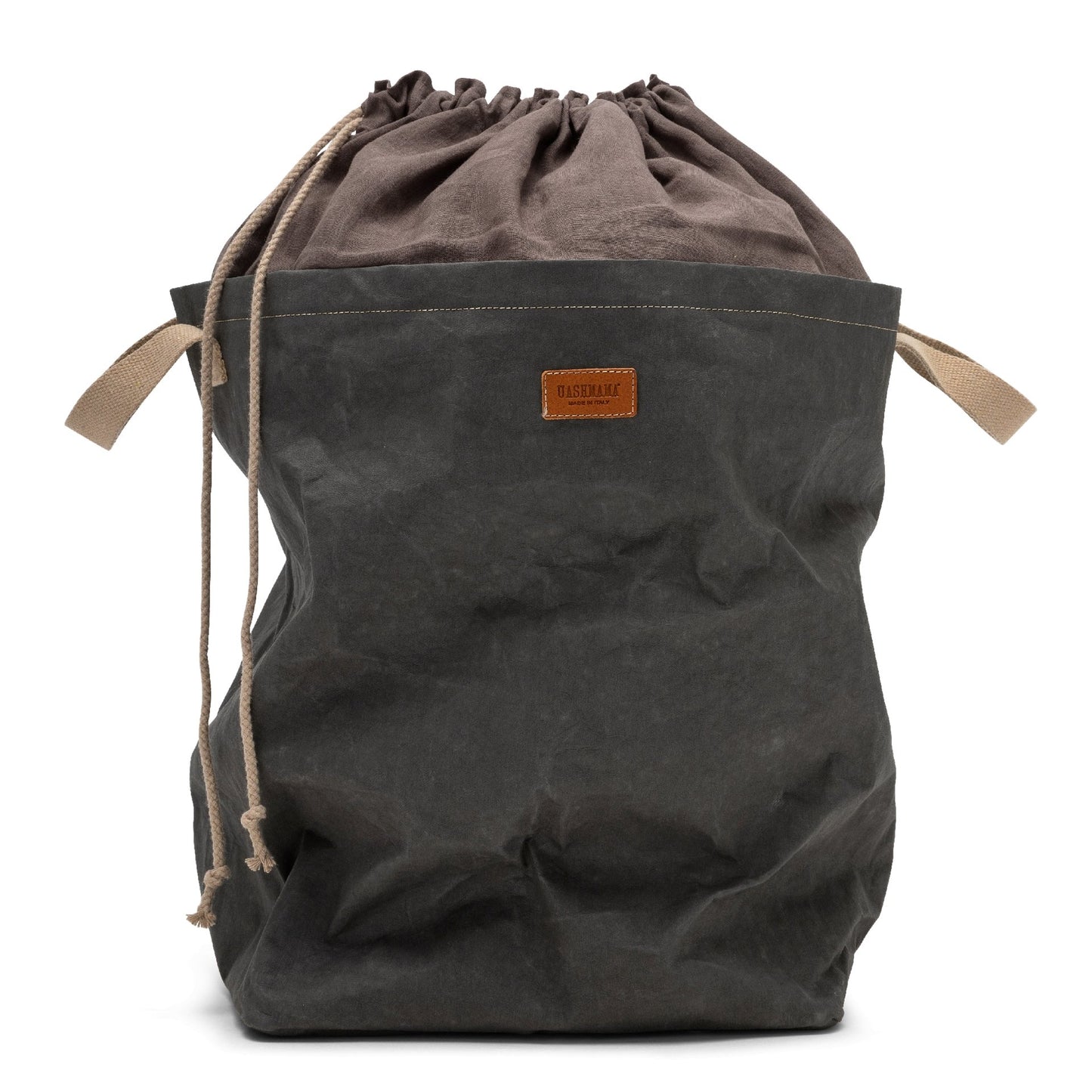 A washable paper laundry bag with a drawstring linen top is shown. The bag has two small recycled cotton handles on either side at the top of the bag, and one drawstring closure at the top. A small leather UASHMAMA logo leather label is on the front of the bag. The bag is dark grey in colour with a dark grey linen drawstring top.