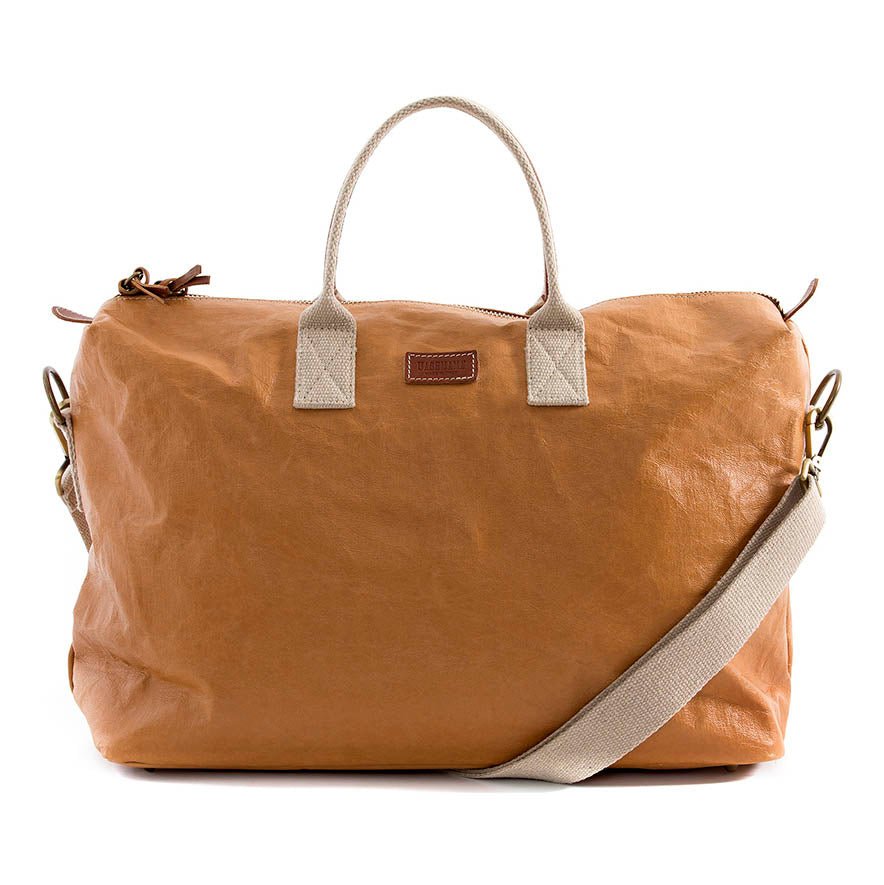 A washable paper holdall with two short carry handles and one long fabric strap. The holdall closes with a zip which has leather zip pulls. The holdall has leather details attaching the straps to the bag and a small UASHMAMA leather logo label. The bag shown is tan. The holdall is large in size.