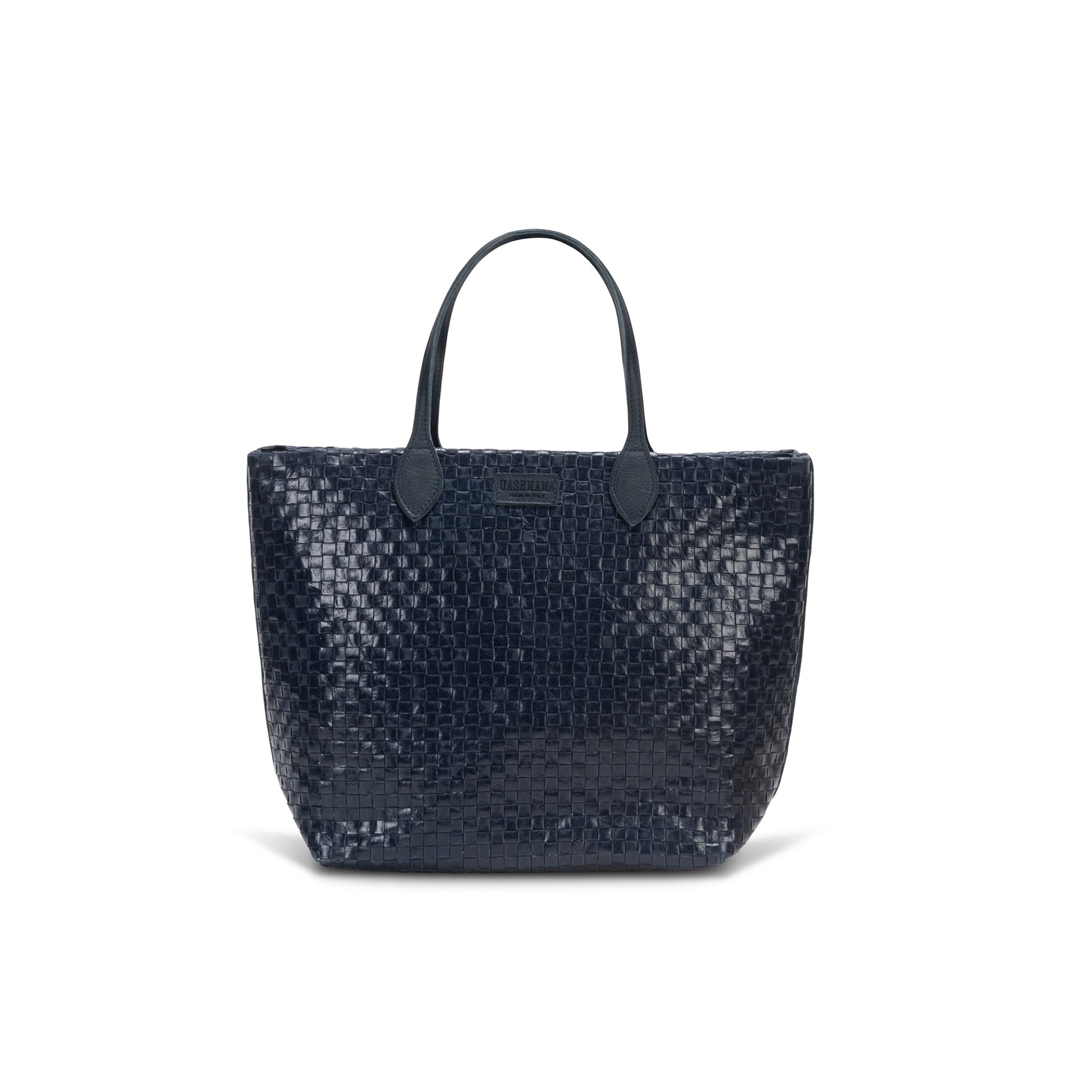 A large washable paper woven tote is shown. It has two long leather handles and a leather UASHMAMA logo label on the outside in between the handles. The bag shown is in a dark blue colour.