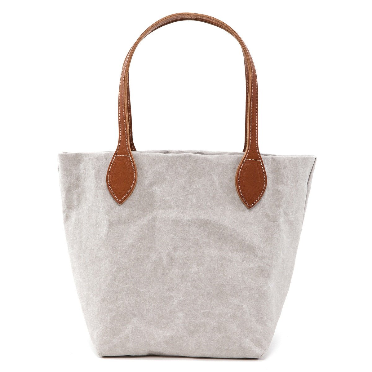 A small washable paper tote is shown. It has two long tan leather handles. The bag shown is pale grey.