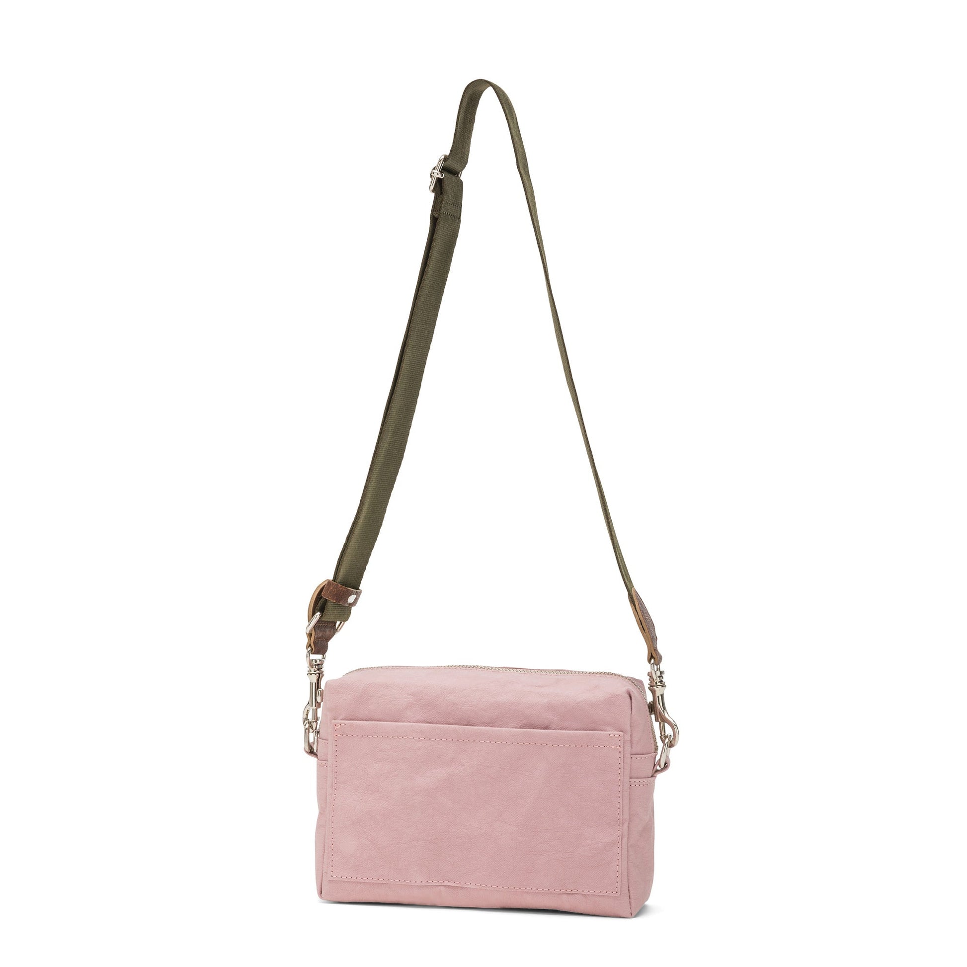 A rectangular washable paper handbag with an external side pocket is shown. The bag has a canvas strap, washable paper details and metal fastening clips to attach the straps to the bag. The bag closes by a zip. The bag shown is pale pink with an olive strap.